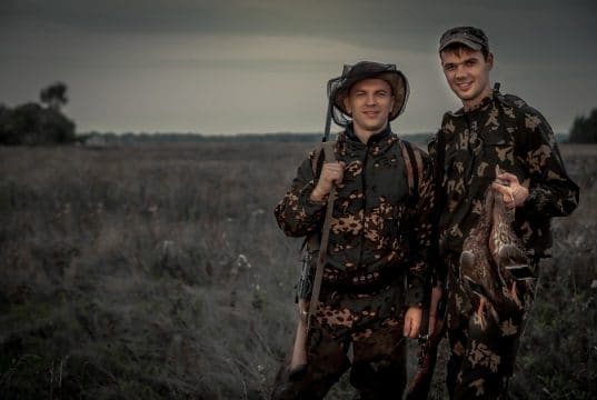 Hunters men with trophy in rural field